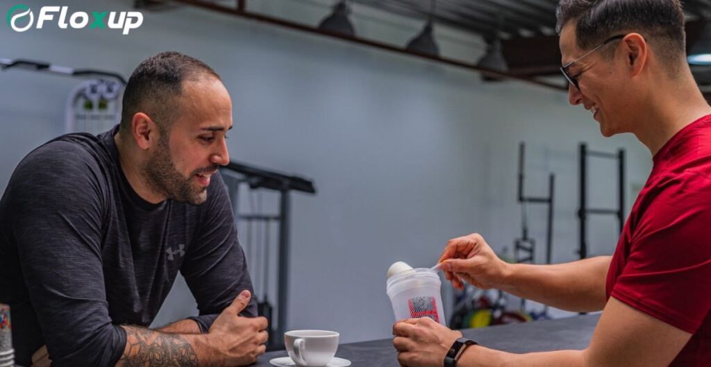 Two men talking in a gym while preparing a protein shake, representing collaboration and partnership opportunities for gyms.